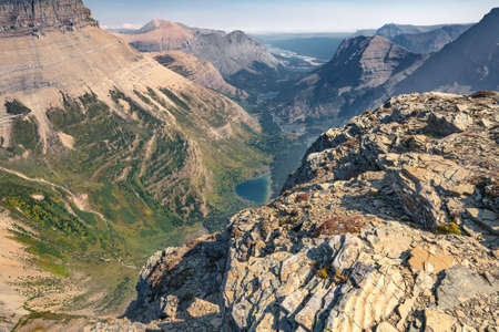 Vast mountain range and valley below in American Rockies on a beautiful sunny day of summer. Epic view from the top of Swiftcurrent mountain in Glacier National Park, Montana, USA.の写真素材