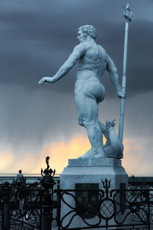 Hel, Polsko - 08.04.2022: Statue of Neptune in port of Hel during golden hour. Sunset with dramatic clouds in the background. Summer holiday at the Baltic coast.のeditorial素材