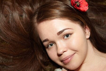 Portrait of the beautiful girl. Red flower in her hairの写真素材