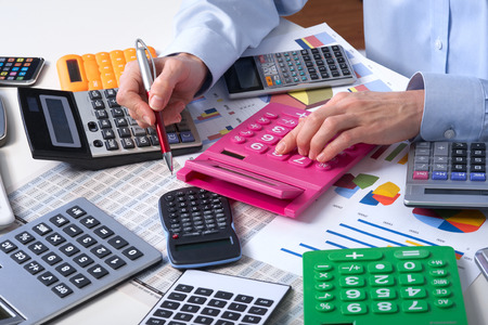 Mature businesswoman and calculators. Calculation at officeの写真素材