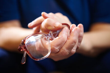 Old woman hands with eyeglasses. Senior people health care.の写真素材