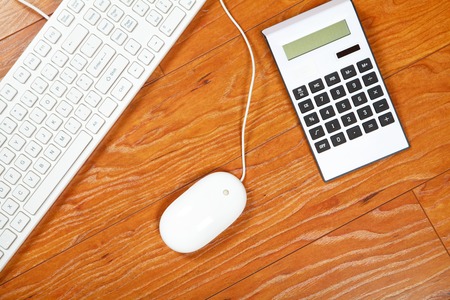 Calculator and keyboard lying on the wooden flooringの写真素材