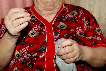 Old woman to sew over a tear