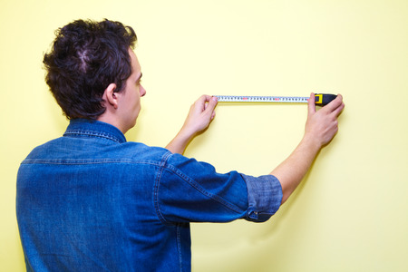 Mature contractor plasterer working indoors in yellow room