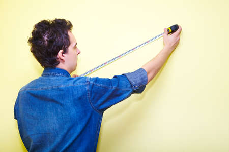 Mature contractor plasterer working indoors in yellow roomの写真素材