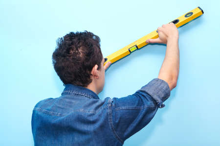 Mature contractor plasterer working indoors in blue room. Construction. Workerの写真素材