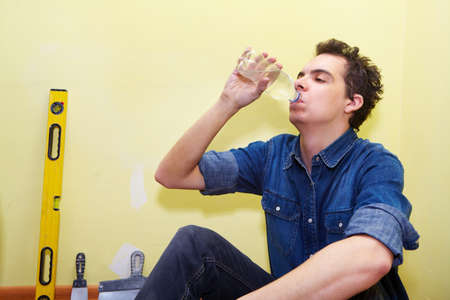 Rest. Mature contractor plasterer working indoors in yellow room