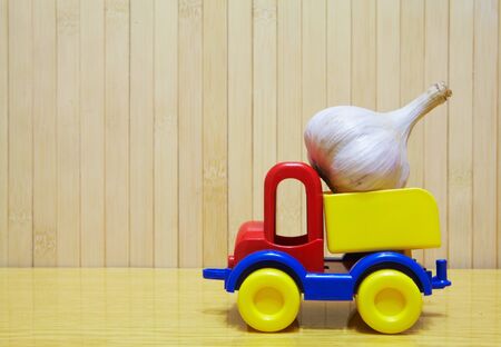 Toy car carrying a garlic on the tableの写真素材