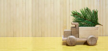 Toy wooden car carrying a christmas tree on the tableの写真素材