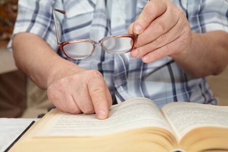 An elderly man with glasses reading a book. Senior people health careの写真素材