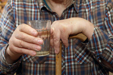 Old man holding a glass of water. Senior people health care