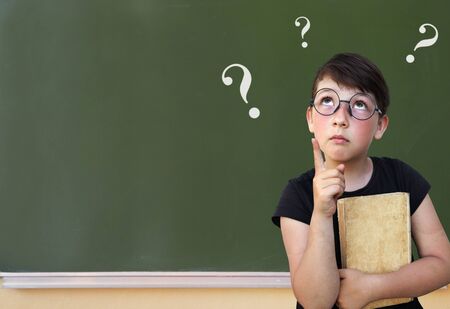 Little girl solves the problem on a blackboardの写真素材