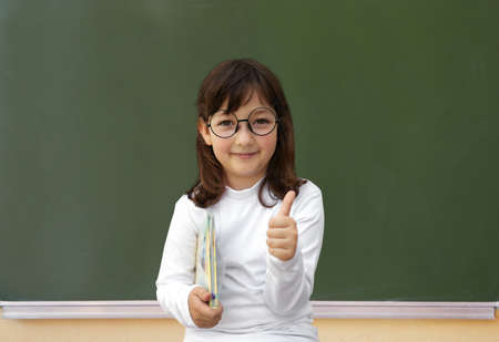 Happy little girl and green blackboard. Ok