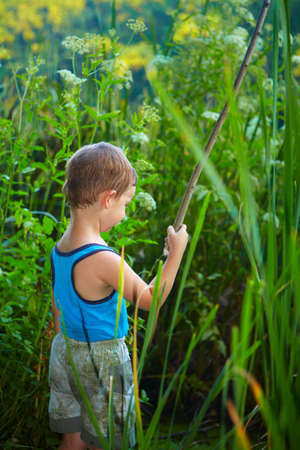 Little boy fishing in a river. Childhood