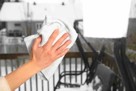 Woman washes a window using a rag 