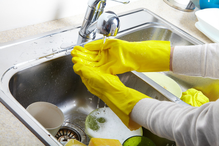Hands washing dishes with running water from faucet in sinkの写真素材