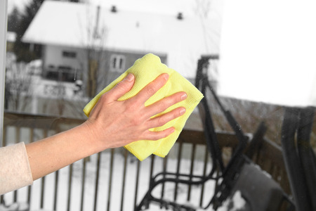 Woman washes a window using a ragの写真素材