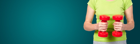 Woman with a dumbbells. On green backgroundの写真素材