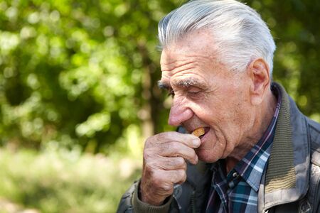 Poverty and bread. Elderly poor man eating breadの写真素材