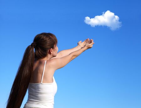 Young girl launches a cloud in the blue skyの写真素材