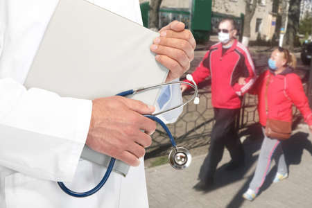 Doctor and people in medical masks on a city street during an epidemic. Znamenka city, Ukraine, 12th of April 2020のeditorial素材