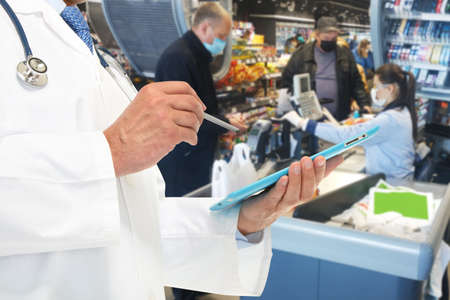 Doctor and people in medical masks in a store during an epidemic. Znamenka city, Ukraine, 12th of April 2020のeditorial素材