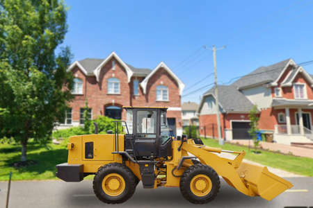 Yellow tractor on a city street. Buildingの写真素材