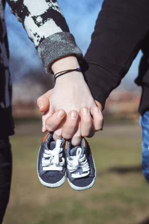 Parents holding hands and baby shoesの写真素材