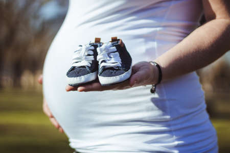 Pregnant woman with baby shoes in handの写真素材