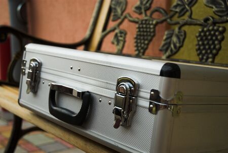 Locked metal suitcase is lying on the benchの写真素材