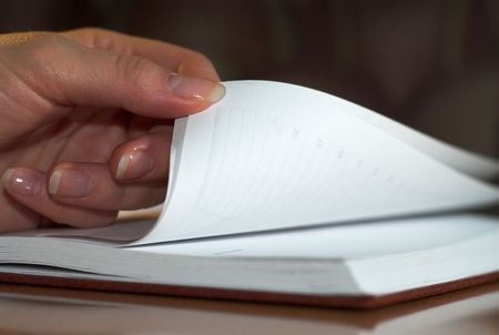 Young woman is turning page in her day book.