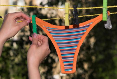 Young woman hanging panty on the clothes lineの写真素材