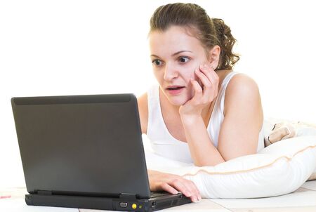 Young girl is surprised in the bed with laptop. Isolated.の写真素材