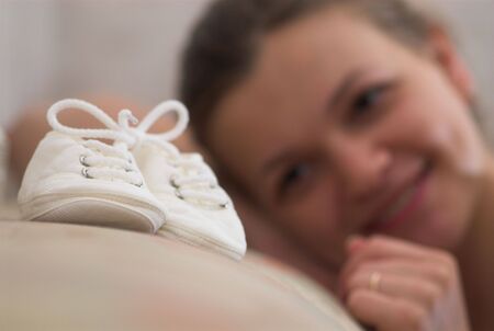 Young pregnant girl looks at baby's booteesの写真素材