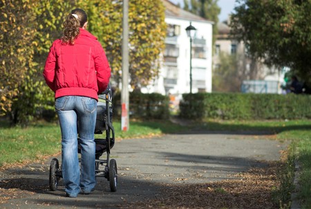 Young mother walks with baby carriage in park