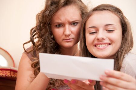 Two teens is reading notes with different emotionsの写真素材