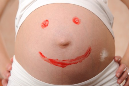 Close-up of pregnant's belly with painted smile signの写真素材