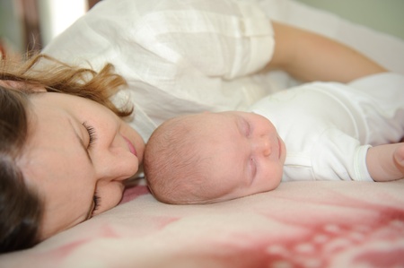 Young mother is sleeping with her little babyの写真素材