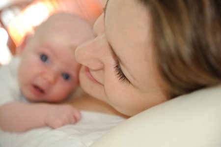 Young mother lying with her little babyの写真素材