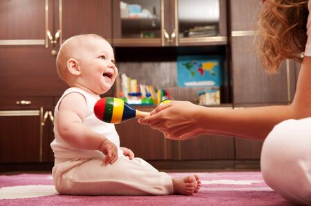 Young mother is playing with her baby n playroomの写真素材