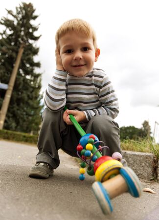 Little cute boy is sitting squat outdoorsの写真素材
