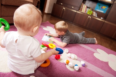 A boy aged 3 and a girl aged 1 are playing on the floorの写真素材