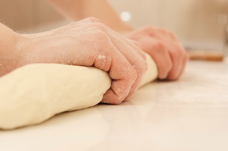 Female cook kneading dough in her kitchen