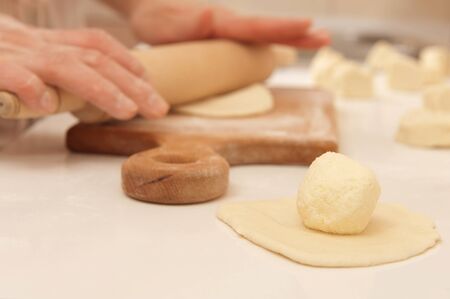 Female cook rolling dough with rolling-pin. Closeup view