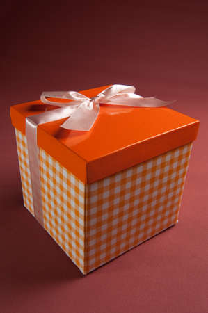 Orange present box with pink bow on textile backgroundの写真素材