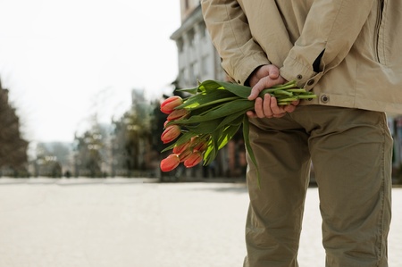 Young man is waiting for his girlfriend with tulipsの写真素材