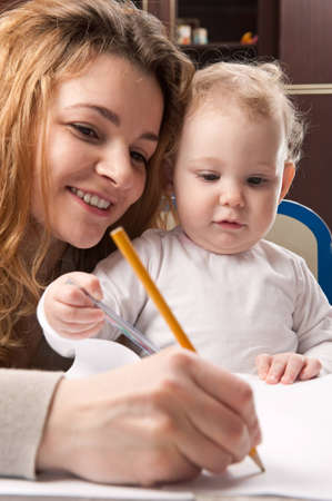 Young mother and her baby daughter drawing with pencilsの写真素材