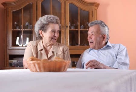 Happy senior couple at the table indoorsの写真素材
