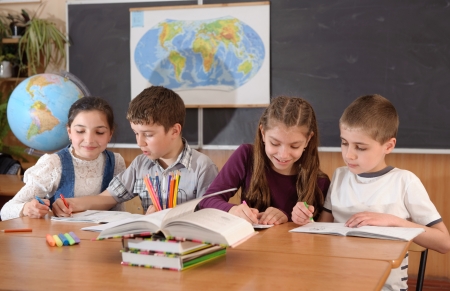 Four schoolchildren aged 11 at the desk in classroomの写真素材
