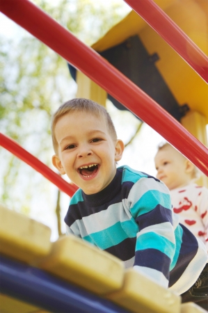 Laughing brother and his little sister on playgroundの写真素材